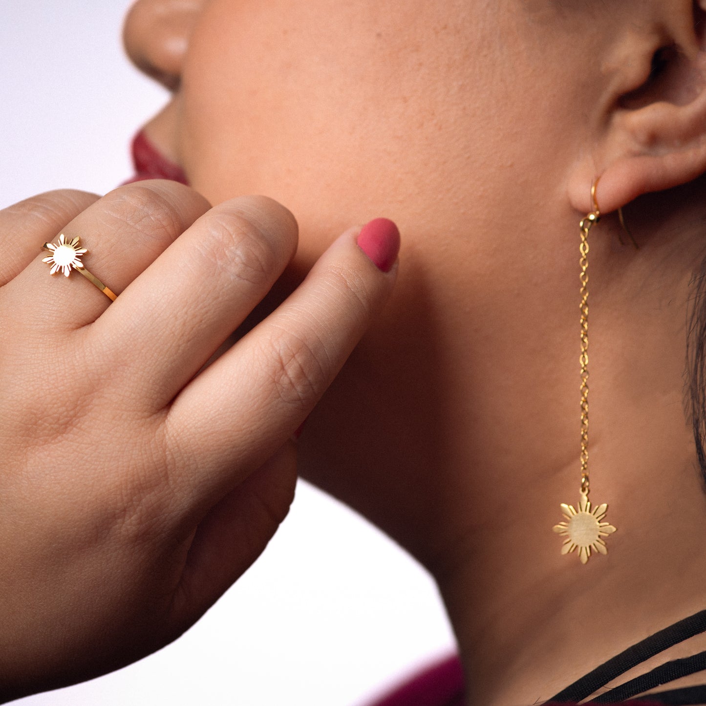 Aking Sinta Araw Adjustable Ring in gold worn on hand placed near face, model with red lipstick in soft-focus background, highlighting adjustable hook and 8-ray sun design