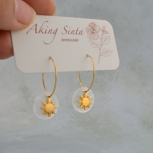 Aking Sinta Araw and Capiz Shell Dainty Hoop Earrings gold variant displayed on branded cardboard holder held by hand, highlighting lightweight design and Philippine-inspired craftsmanship