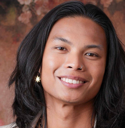 Aking Sinta Araw Hook Earrings with 8-ray sun charms worn by man with long hair, earrings slightly covered, highlighting lightweight design and Philippine-inspired craftsmanship