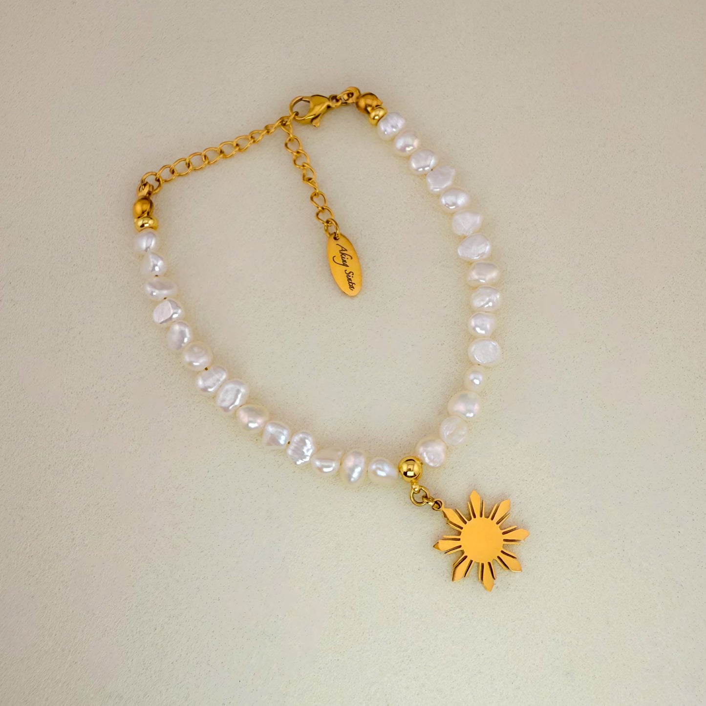 Aking Sinta Baroque pearl bracelet with a gold Philippine 'Araw' sun charm, displayed on a minimalist white background.