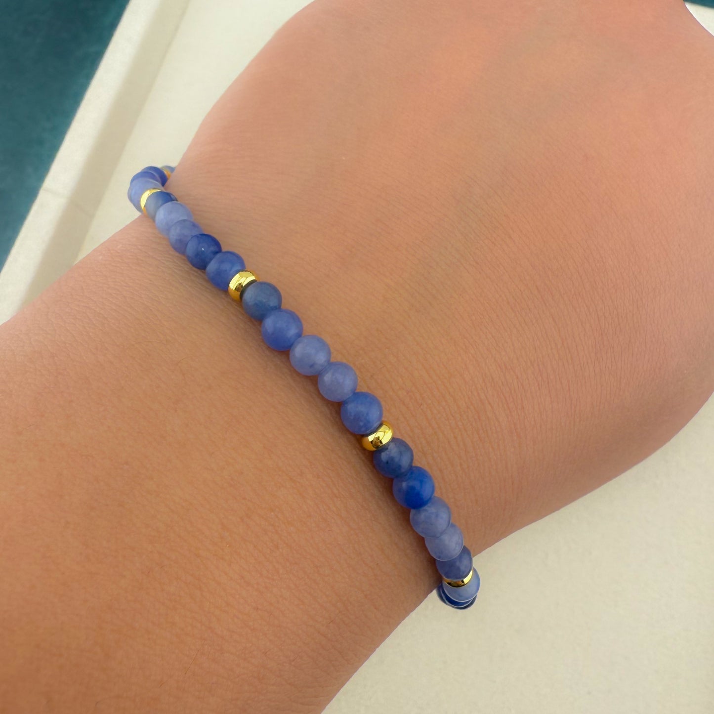 A close-up of an Aking Sinta Blue Aventurine beaded bracelet on a clenched fist; the focus is on the uniform misty blue gemstones wrapped around the wrist, presenting a clean, bold, and gender-neutral aesthetic without a charm or visible hardware
