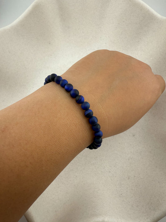 Aking Sinta Blue Tiger Eye stretch bracelets worn on a wrist; the dark midnight-blue beads show a silky natural shimmer, with the charms tucked out of view.