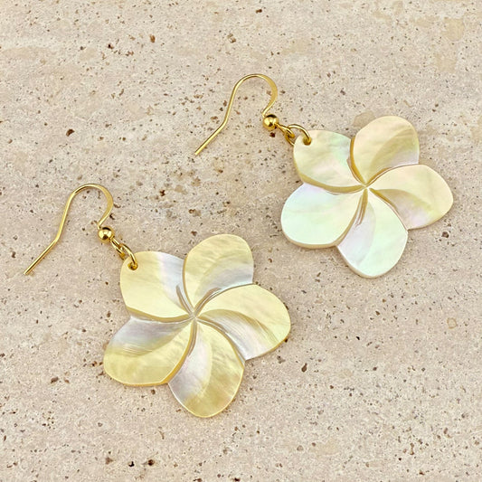 Extreme macro close-up of an Aking Sinta Kalachuchi earring, showing the intricate hand-carved petals of the Mother of Pearl flower and its iridescent luster on a marble background.