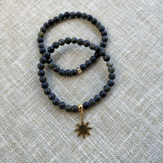Aking Sinta Matte Serpentine Stretch Bracelet in gold, plain and with Araw charm, displayed on woven grey textured background, highlighting natural stone design