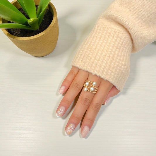 Close-up of a hand wearing the Aking Sinta Multi-Pearl adjustable gold coiled ring on the middle finger; styled with a jacket sleeve for a modern look.