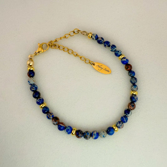 A minimalist Aking Sinta Brilliant Blue Imperial Jasper beaded bracelet without a charm, featuring vibrant aqua gemstone beads with natural marbled patterns; includes a gold extender chain with an engraved "Aking Sinta" teardrop tag.
