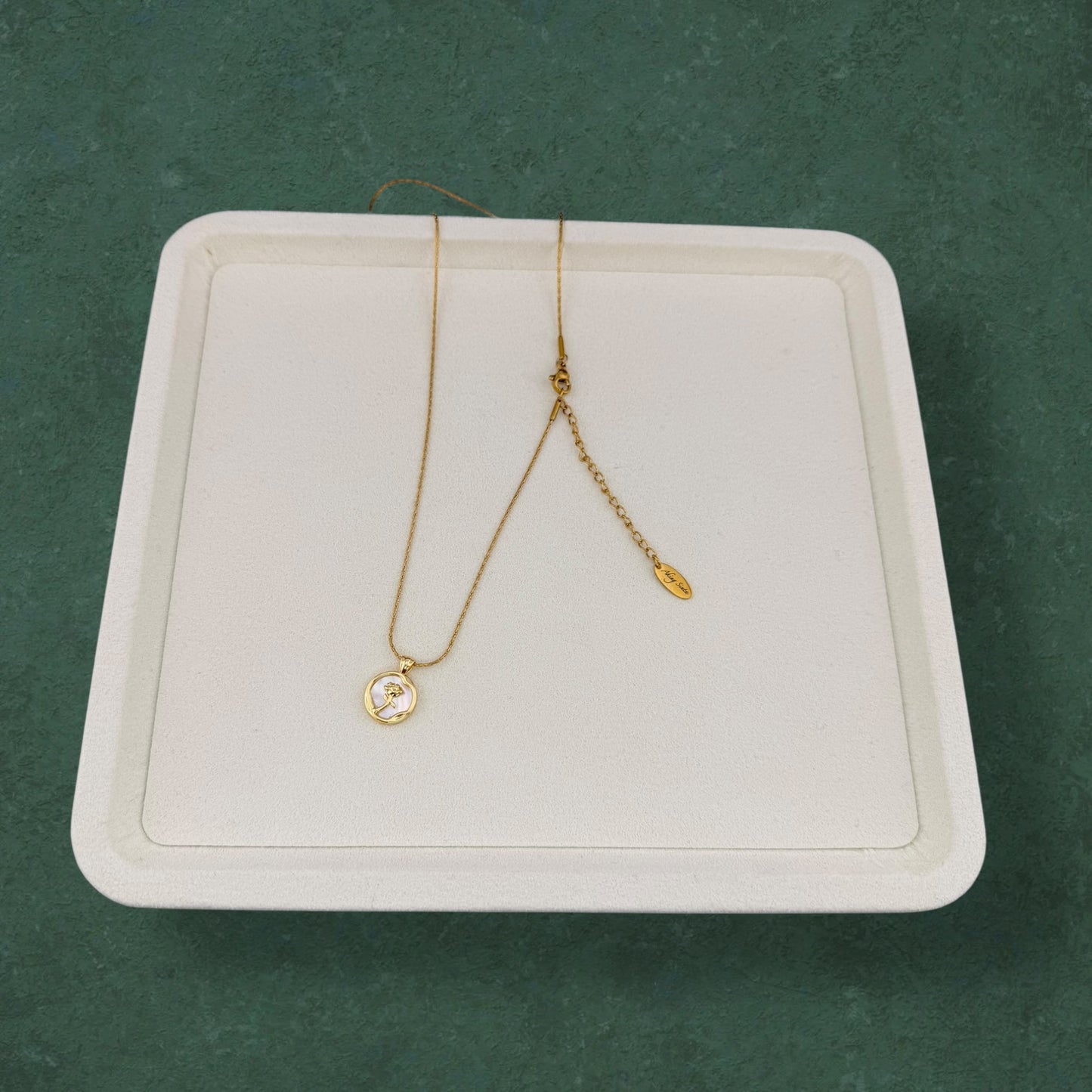 Rose and Mother of Pearl necklace arranged on elegant tray, featuring floral pendant and natural pearl accents in a luxurious presentation