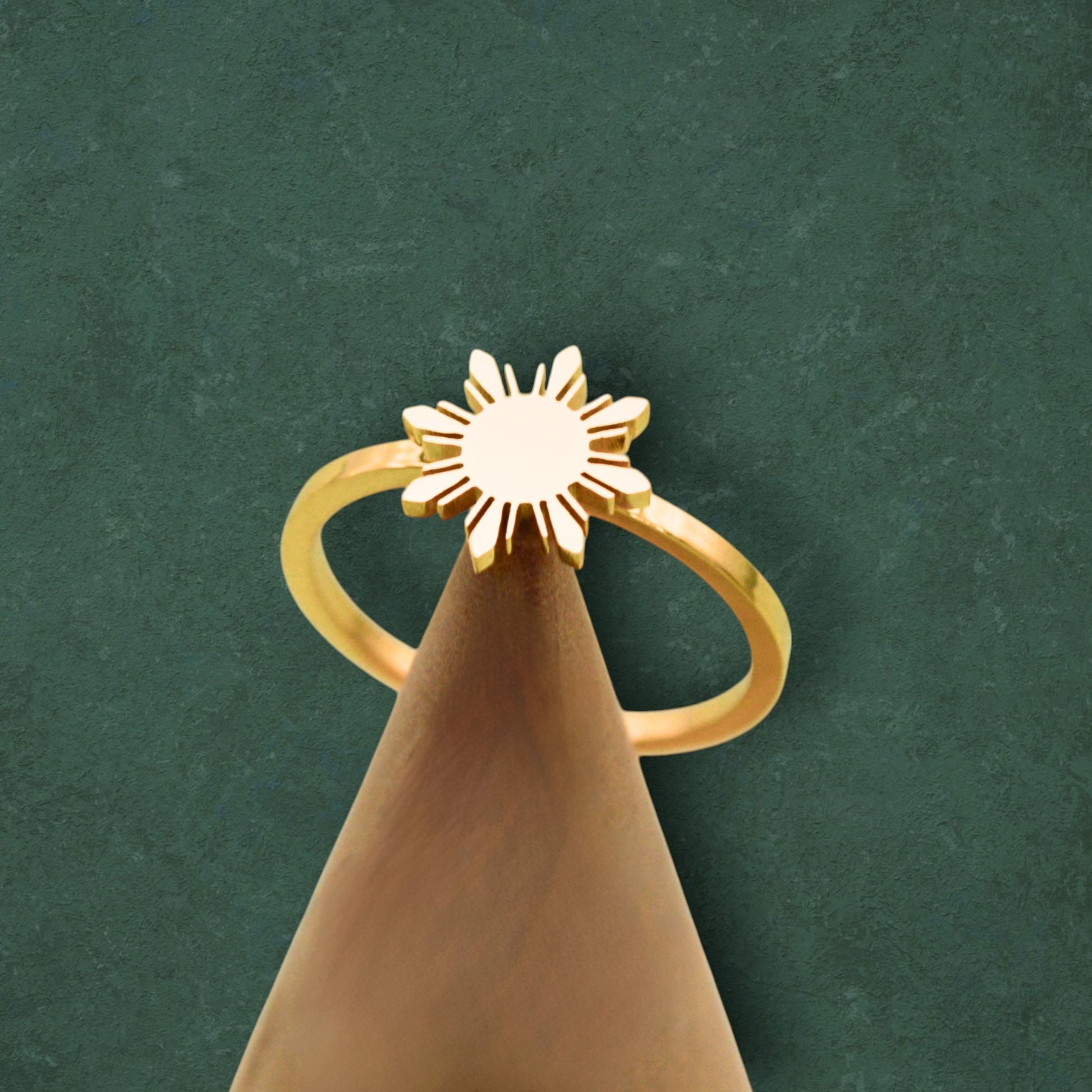 Aking Sinta Araw Adjustable Ring in gold displayed on cone-shaped stand on dark green background, Philippine-inspired jewellery with 8-ray sun design