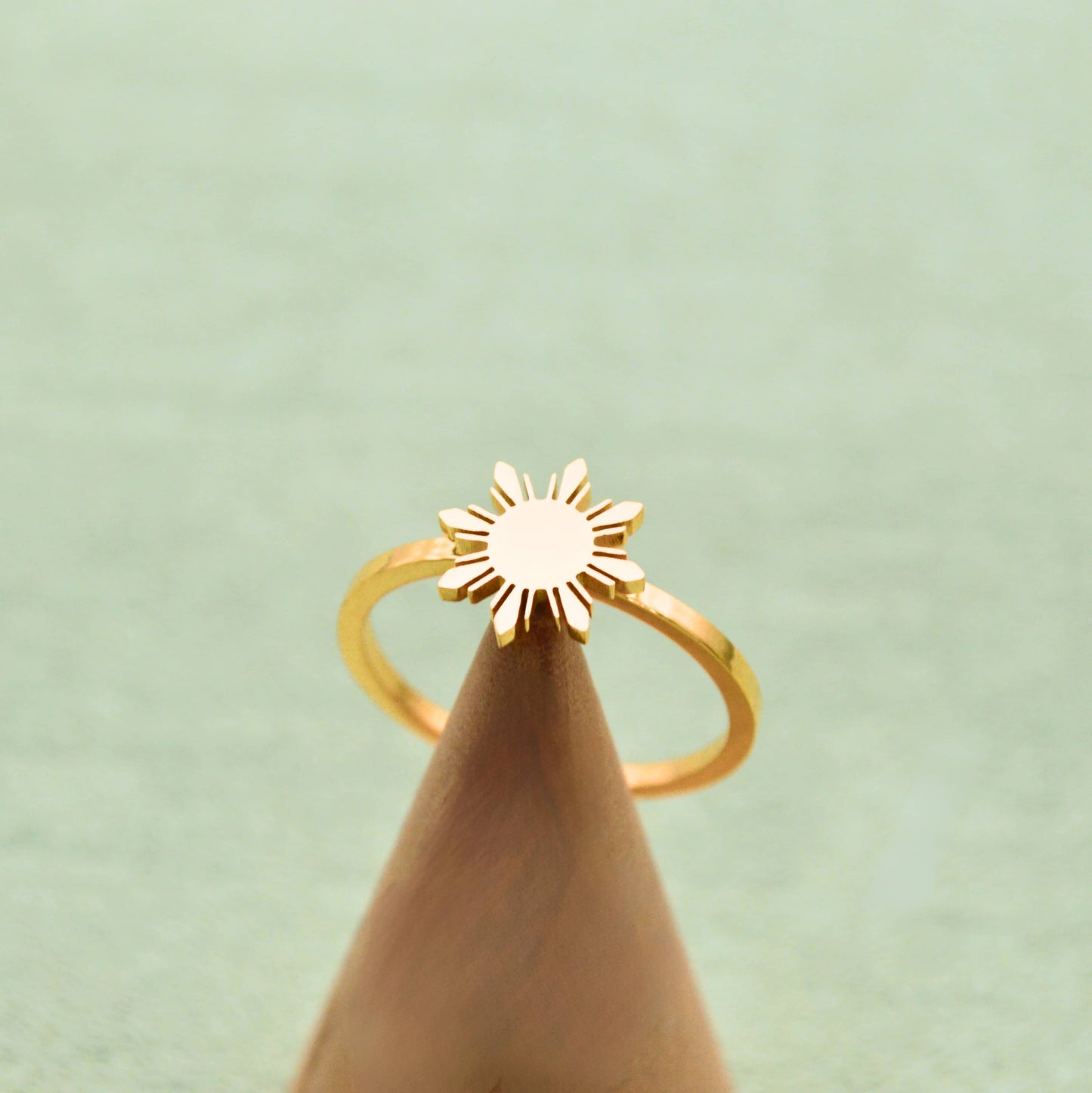 Aking Sinta Araw Adjustable Ring in gold displayed on cone-shaped stand on light green background, highlighting 8-ray sun design and adjustable hook feature