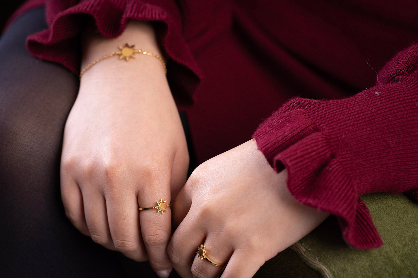 Aking Sinta Araw Adjustable Ring in gold worn on right ring finger and left pointer finger, model in red dress in soft-focus background, showcasing adjustable hook and 8-ray sun design
