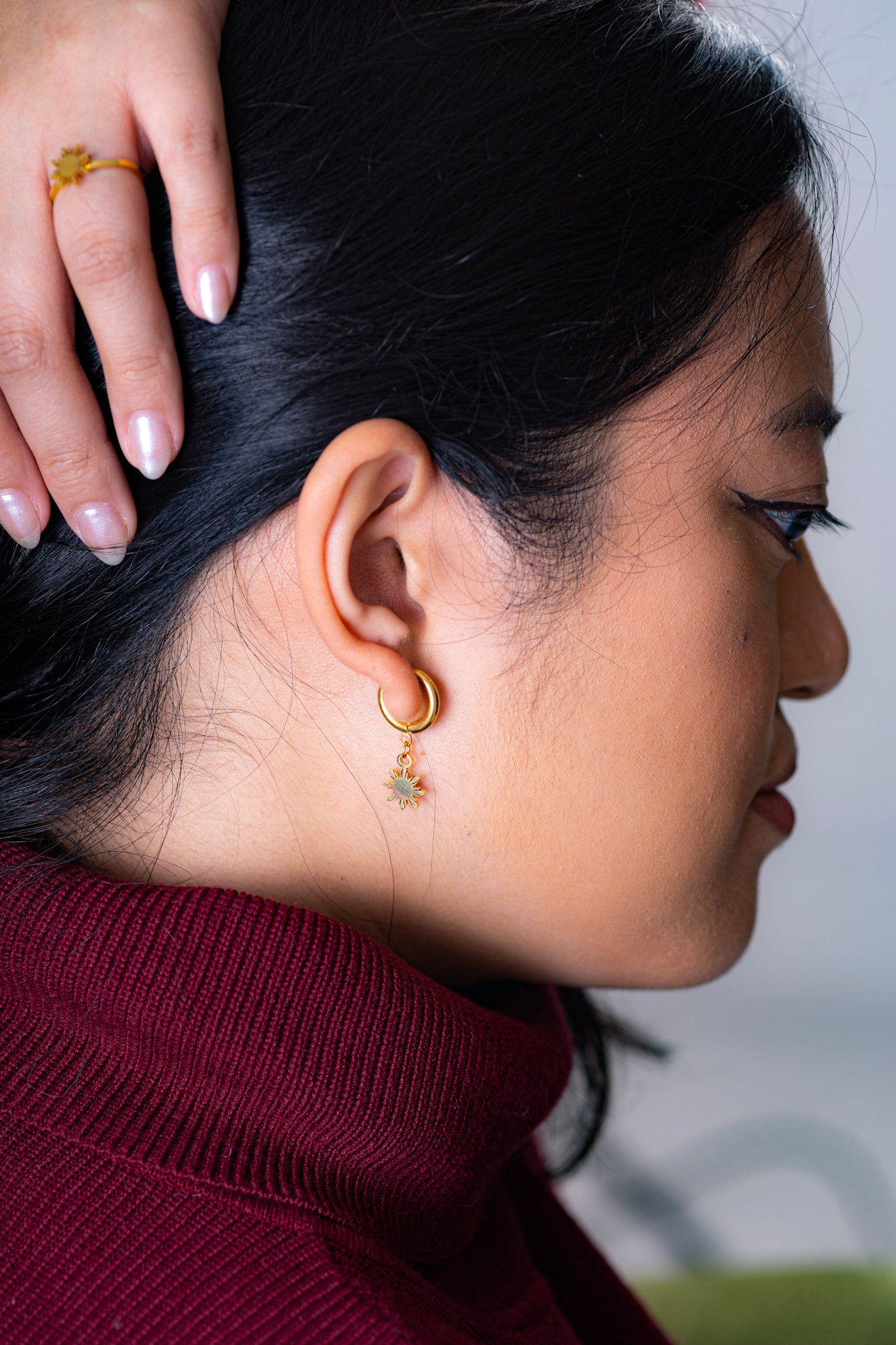 Aking Sinta Araw Adjustable Ring in gold worn by woman in red dress lifting hand to reveal ring, highlighting adjustable hook and 8-ray sun design