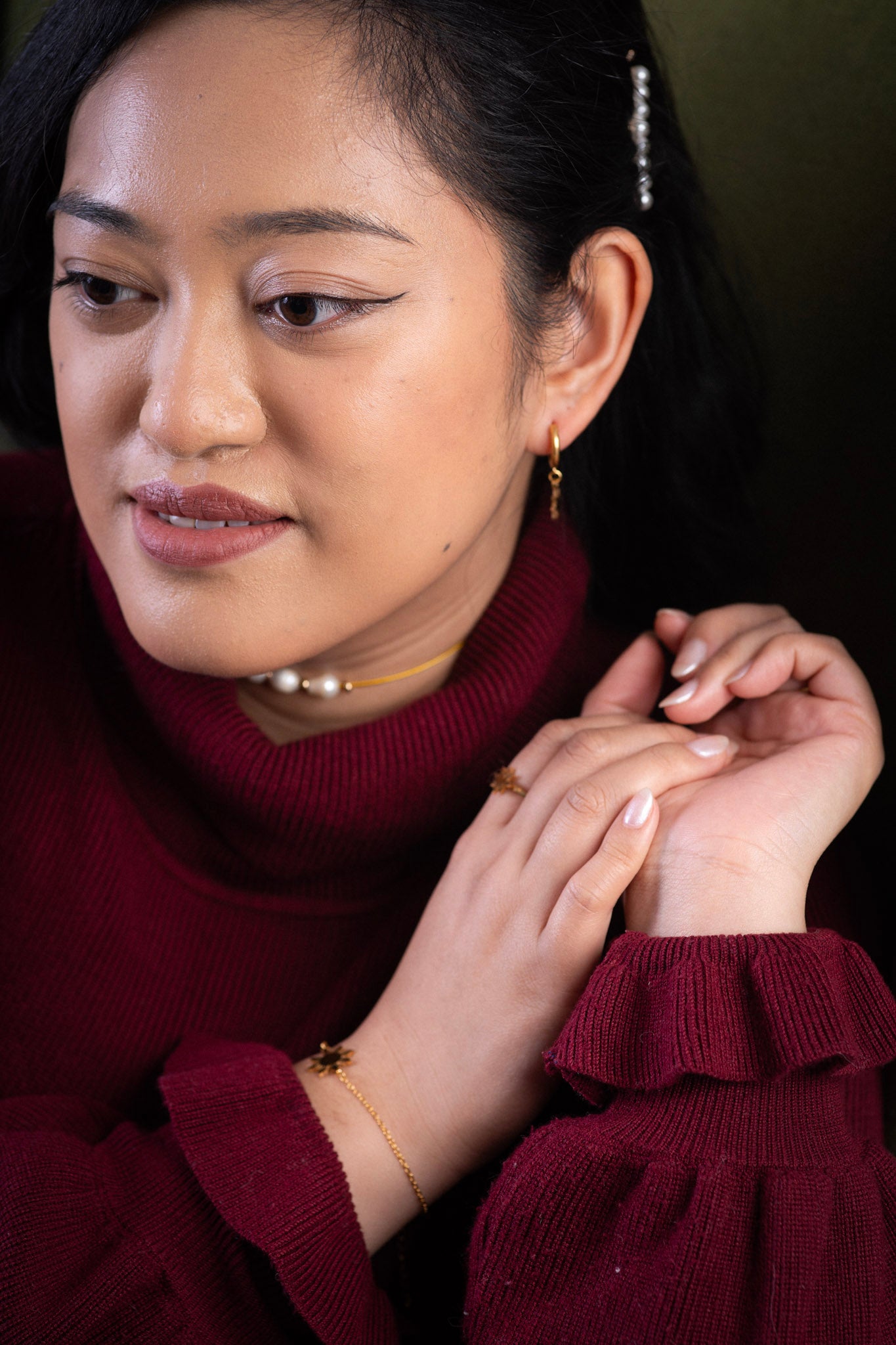 Aking Sinta Araw Charm Huggies in gold inspired by the 8-ray sun worn by woman in dark red attire