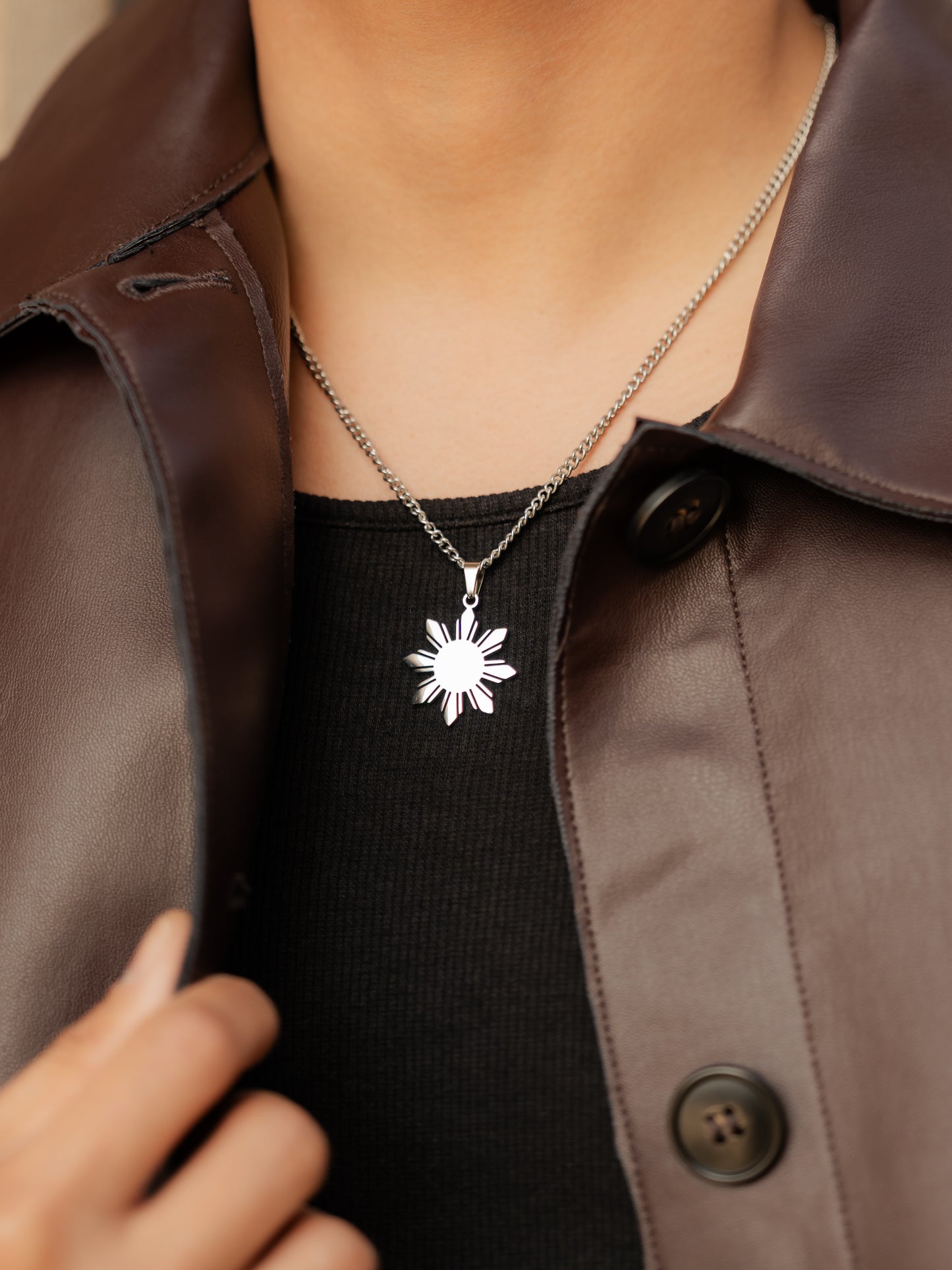 Aking Sinta Araw Chunky Curb Chain Necklace silver variant worn by man in black outfit with brown leather jacket, highlighting 8-ray sun pendant charm and bold, Philippine-inspired design