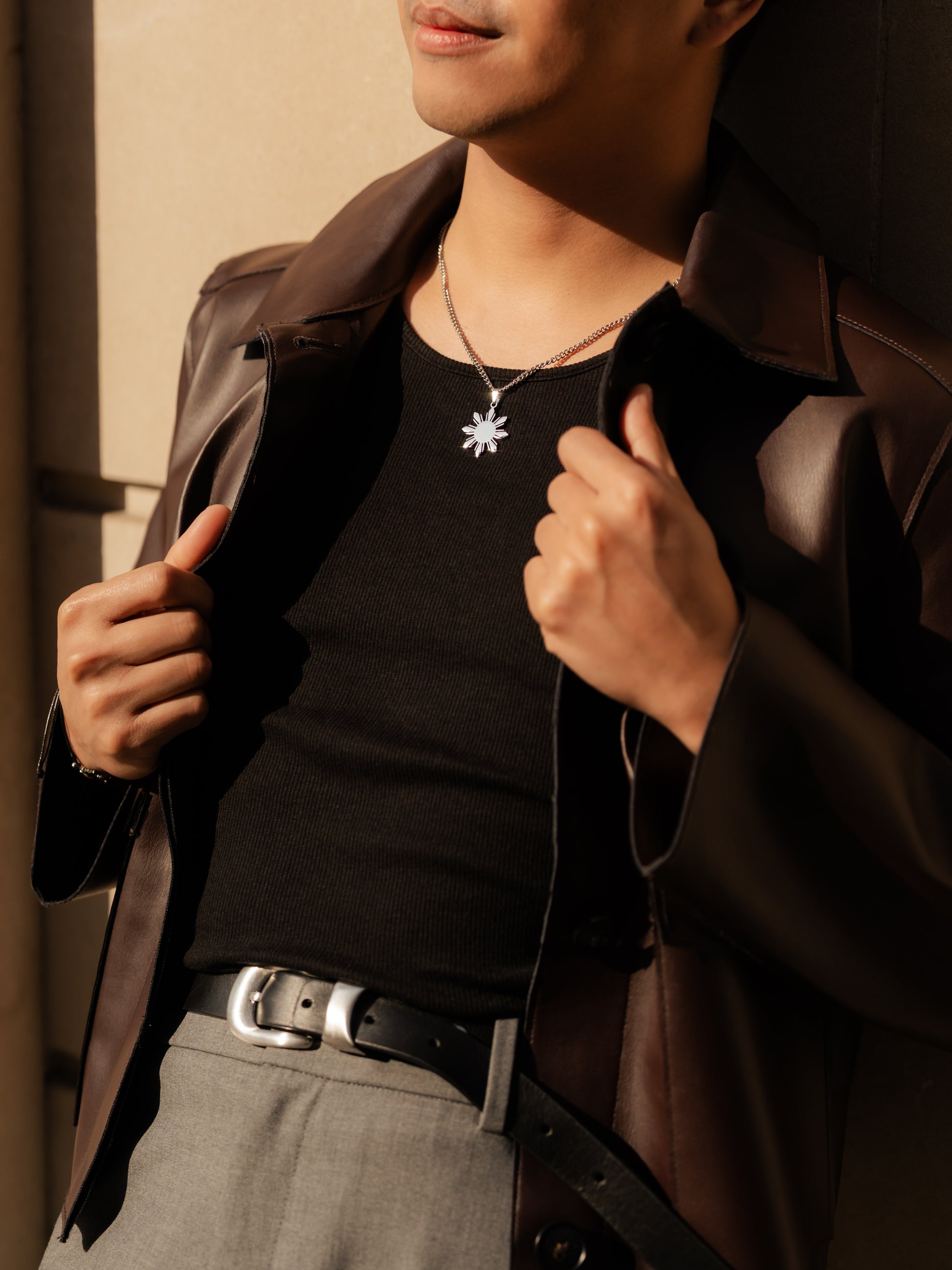 Aking Sinta Araw Chunky Curb Chain Necklace silver variant worn by man leaning on wall, highlighting 8-ray sun pendant charm and bold, Philippine-inspired design