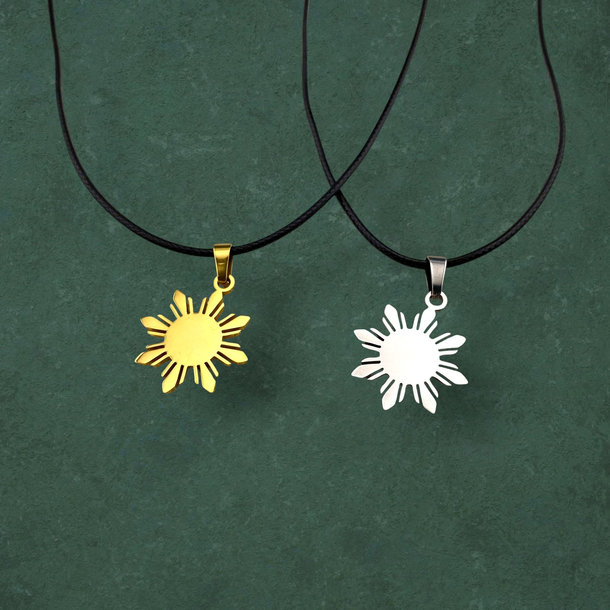 Aking Sinta Araw Cord Necklace with black cord in silver and gold variants displayed on dark green background, highlighting adjustable cord design and Philippine-inspired sun charm