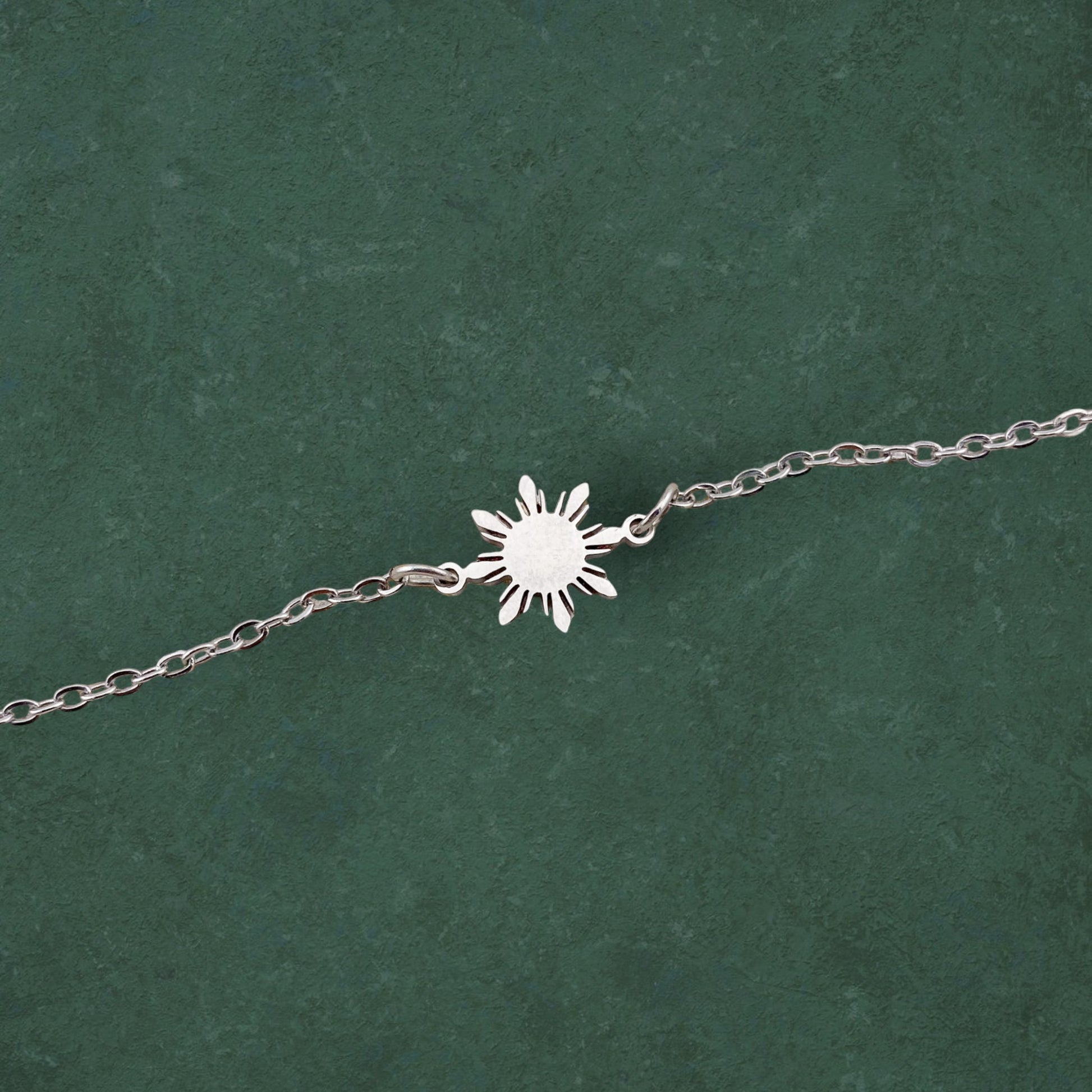Aking Sinta Araw Minimalist Anklet silver variant displayed on green background, highlighting delicate sun charm and minimalist design