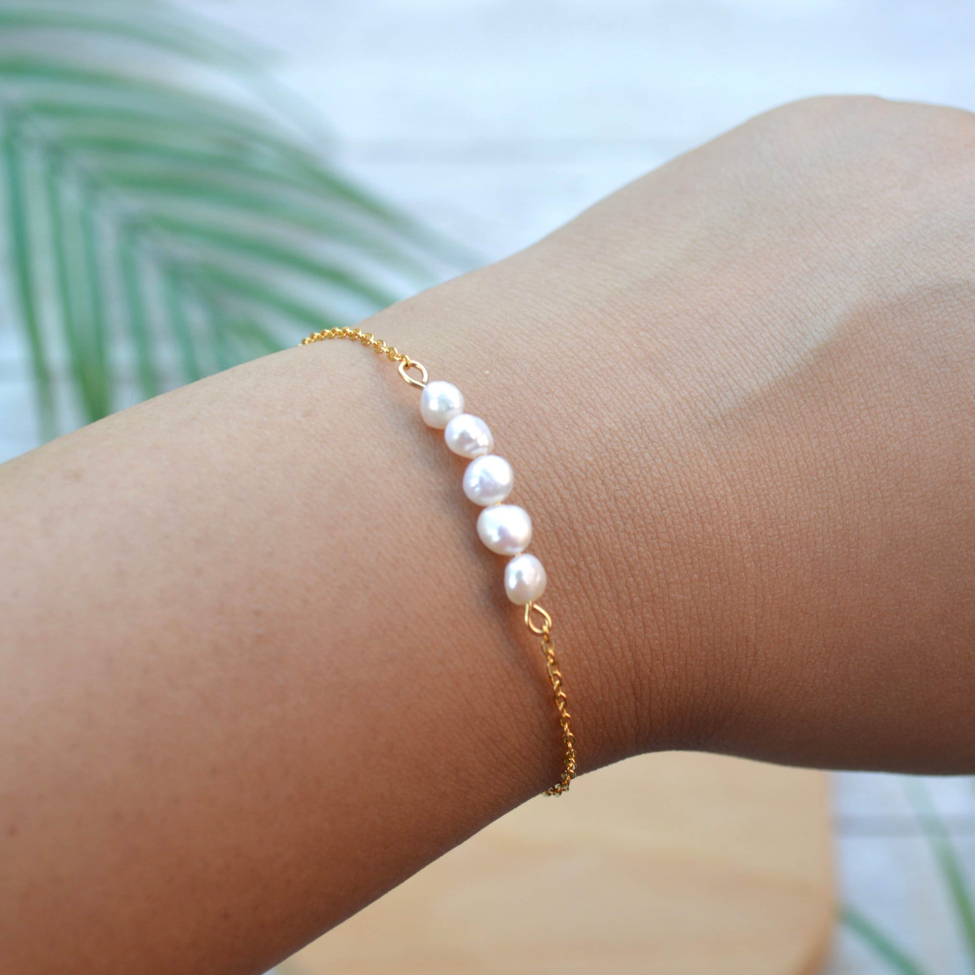 Aking Sinta gold chain bracelet with five organic Baroque pearls worn on a wrist; featuring irregular-shaped iridescent pearls and a high-shine link chain.