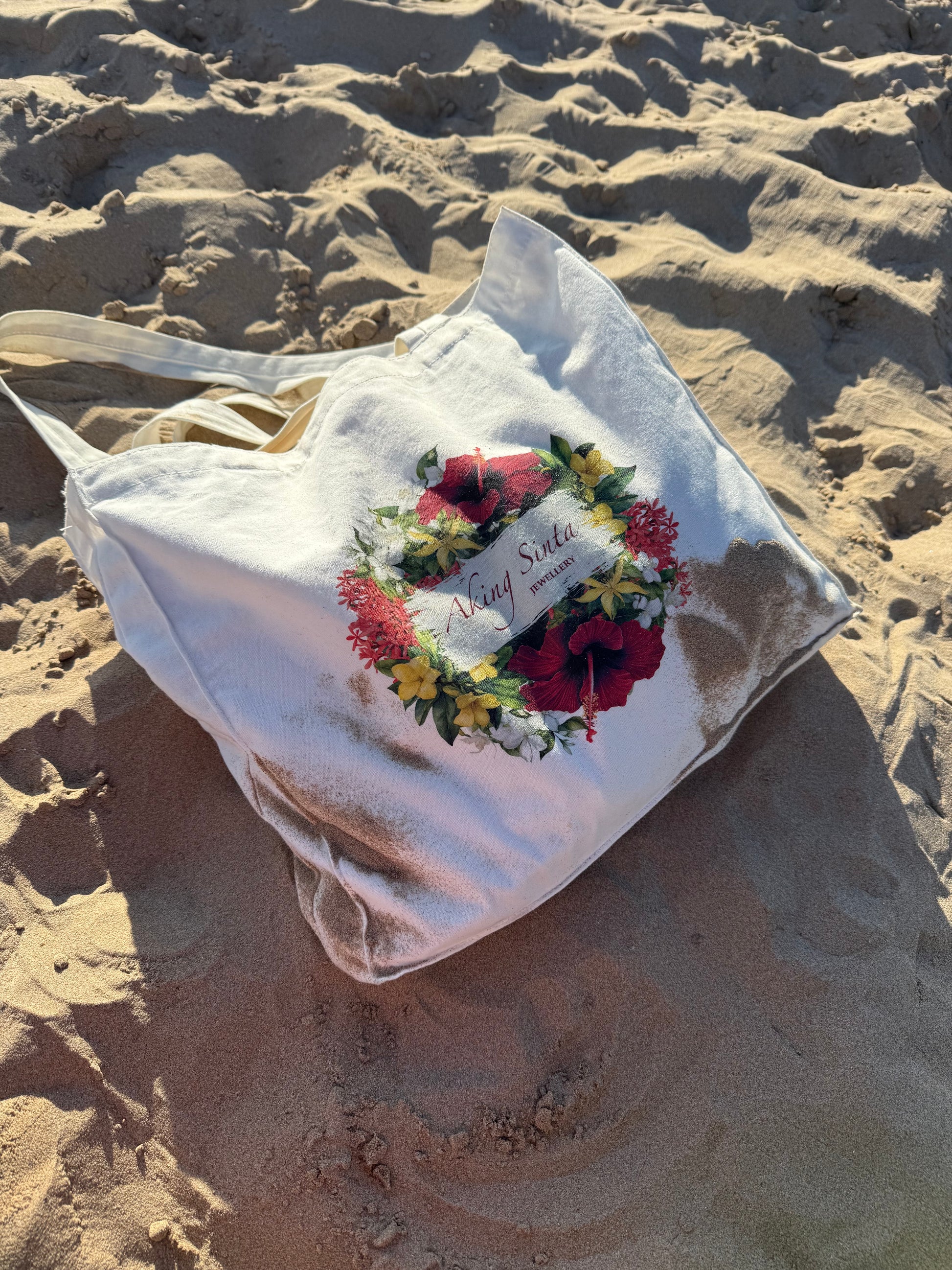 Aking Sinta ‘BET on Yourself’ Floral Tote Bag on white sandy beach, showcasing Philippine-inspired blooms and empowering mantra in a lifestyle setting