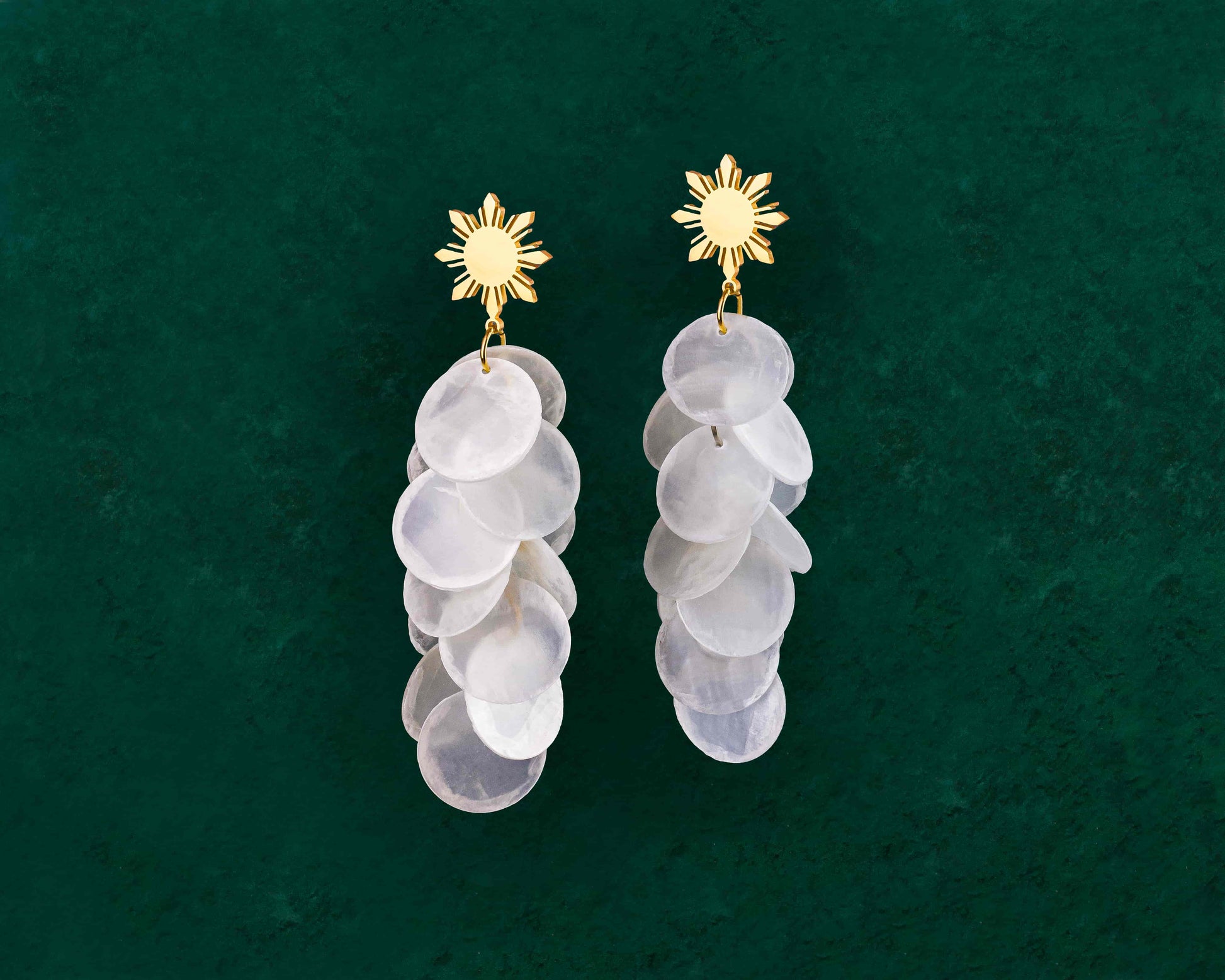 Aking Sinta Cascading Capiz Shell Araw Stud Earrings gold variant displayed on dark green background, highlighting lightweight design and Philippine-inspired craftsmanship