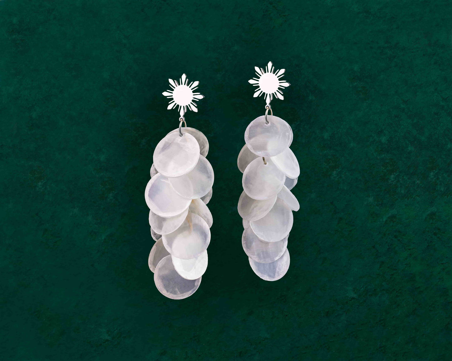 Aking Sinta Cascading Capiz Shell Araw Stud Earrings silver variant displayed on dark green background, highlighting lightweight design and Philippine-inspired craftsmanship