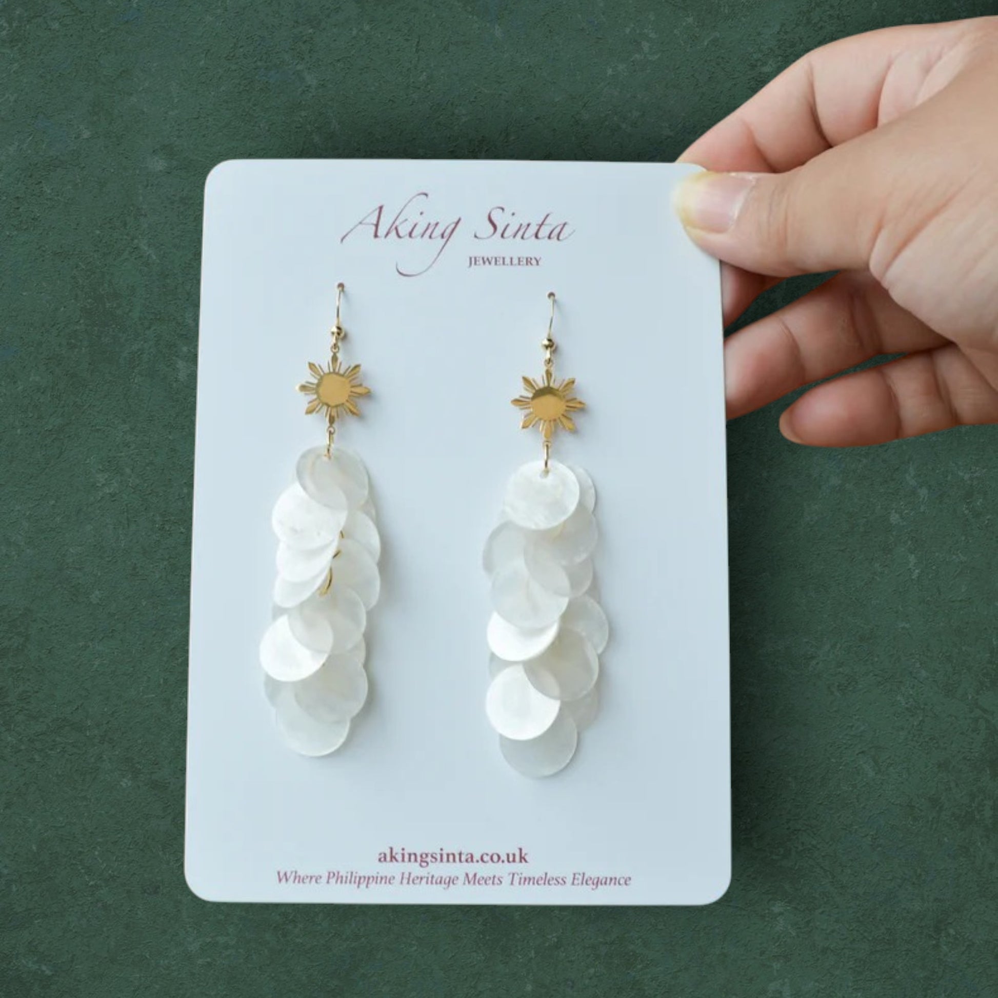 Aking Sinta Cascading Capiz Shell Hook Earrings with Araw sun charms displayed on branded cardboard holder with Aking Sinta logo at top, highlighting lightweight design and Philippine-inspired craftsmanship