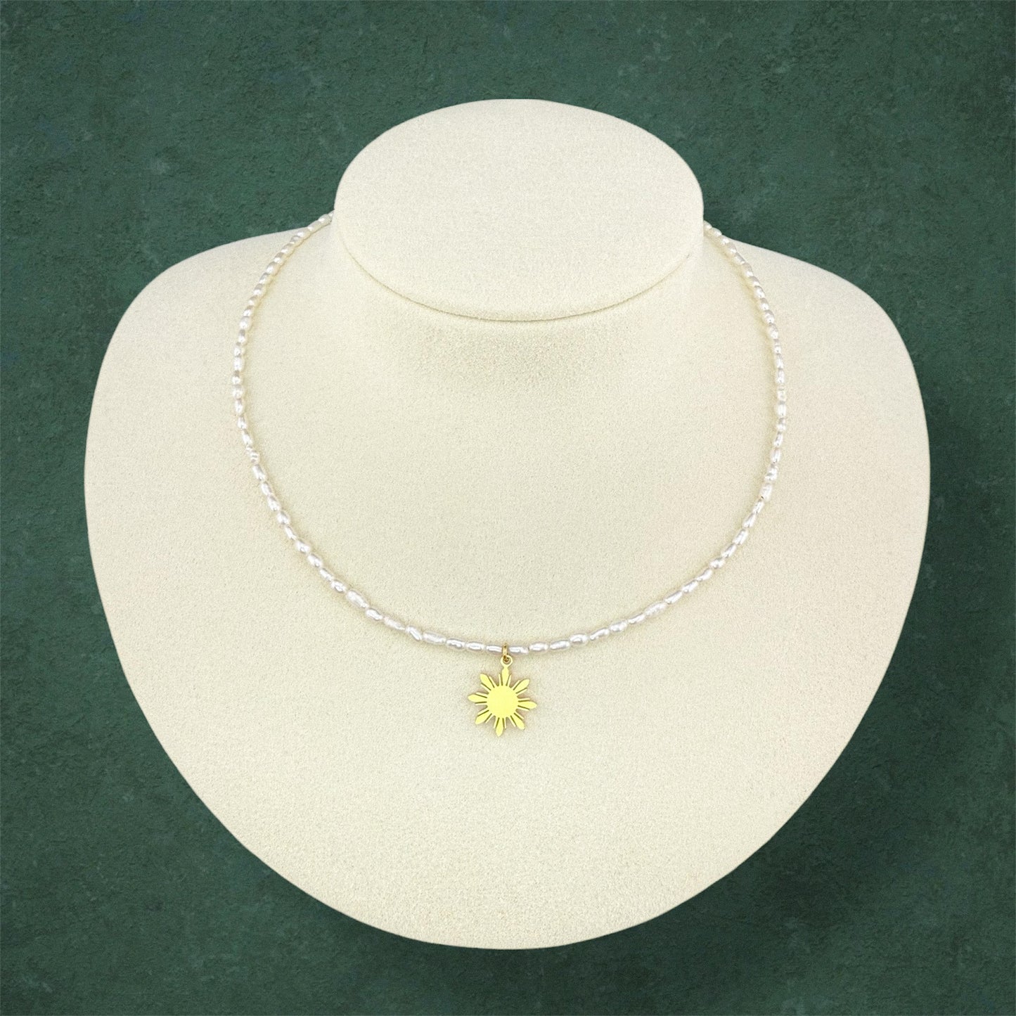 Aking Sinta rice pearl necklace featuring a gold Philippine 'Araw' sun charm, displayed on a white jewelry bust.