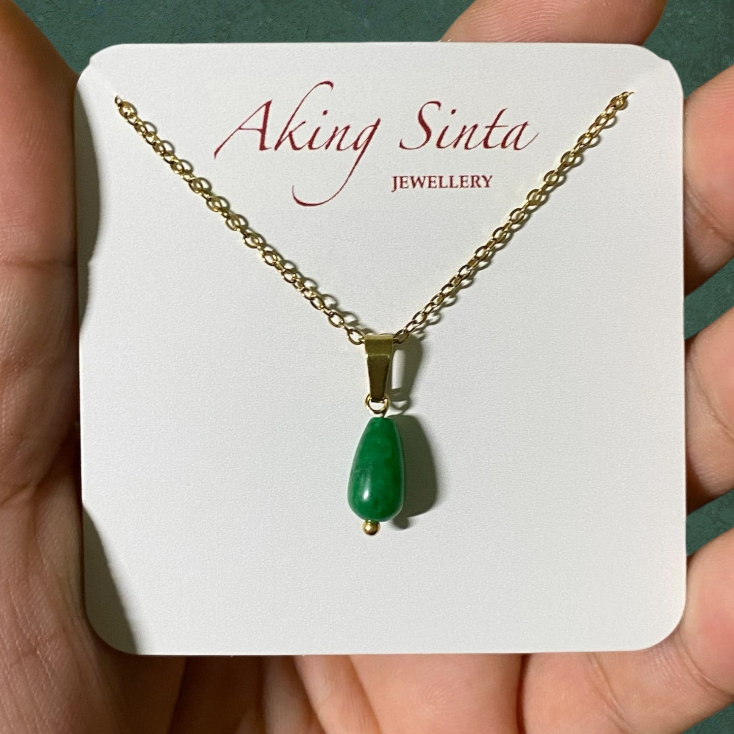 Close-up of Aking Sinta Dainty Teardrop Jade Chain Necklace on branded cardboard jewellery holder, highlighting teardrop jade pendant and delicate chain design
