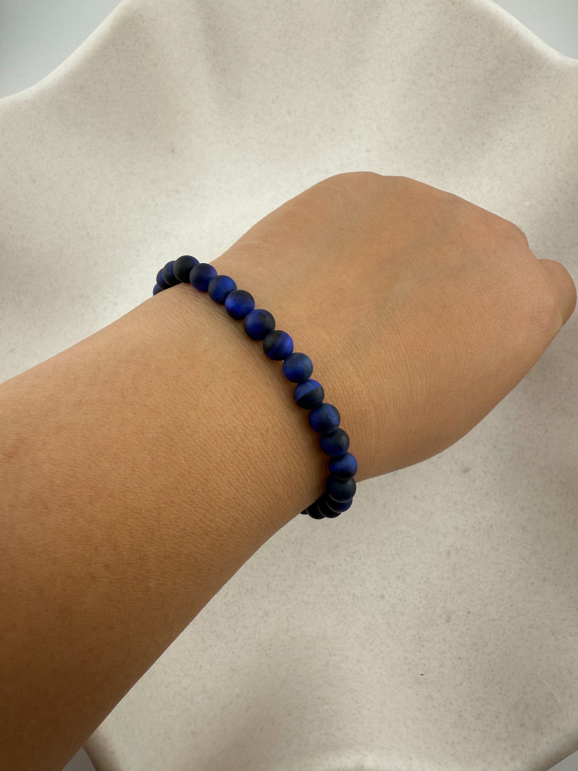 Aking Sinta Blue Tiger Eye stretch bracelets worn on a wrist; the dark midnight-blue beads show a silky natural shimmer, with the charms tucked out of view.