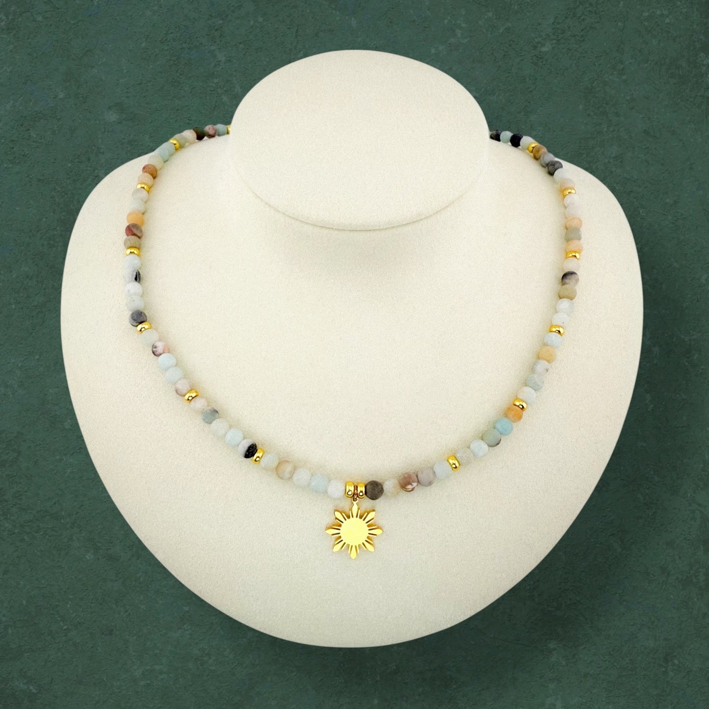 Aking Sinta Flower Amazonite necklace on a white display bust; featuring cream, light blue, and speckled green beads with gold accents and a central gold 8-ray Araw sun charm.