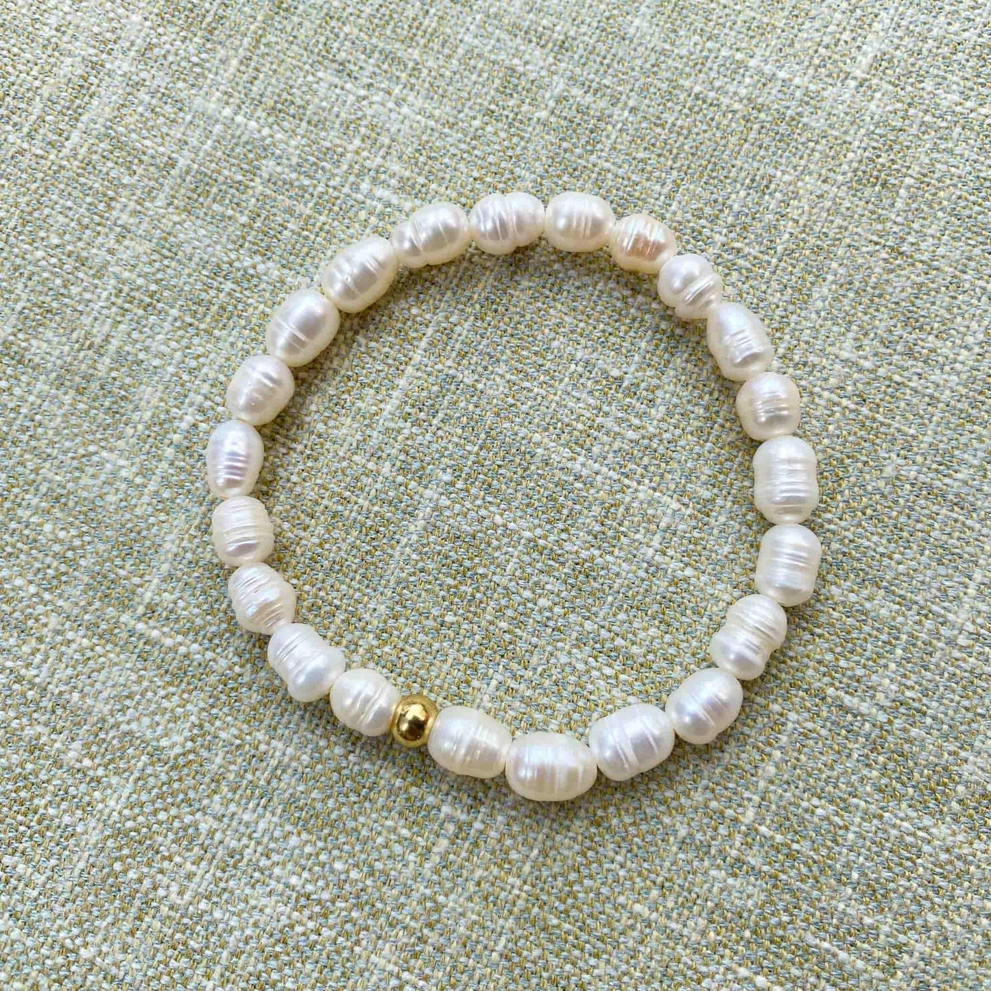 Aking Sinta Freshwater Pearl Stretch Bracelet with white beads, no charm, displayed on woven textured background, highlighting natural stone beads and stretch design