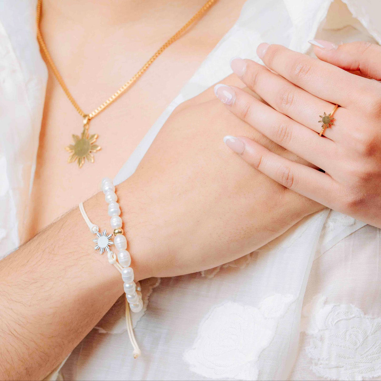 Close-up of hands wearing Aking Sinta Freshwater Pearl Stretch Bracelet with white beads and silver Araw charm, worn by model in white polo, highlighting bracelet