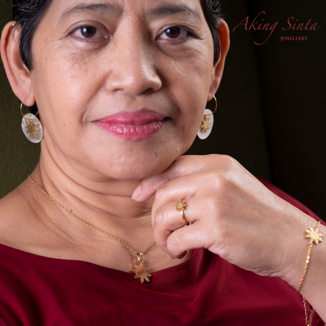 Aking Sinta full Araw jewellery set in gold worn by mother of the founder in red dress, featuring studs, necklace, bracelet and adjustable ring with 8-ray sun design