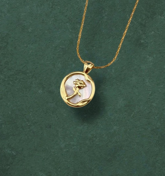 Aking Sinta necklace featuring a layered pendant with a gold rose blossom in front of a round iridescent Mother of Pearl disc, displayed on a dark green background.