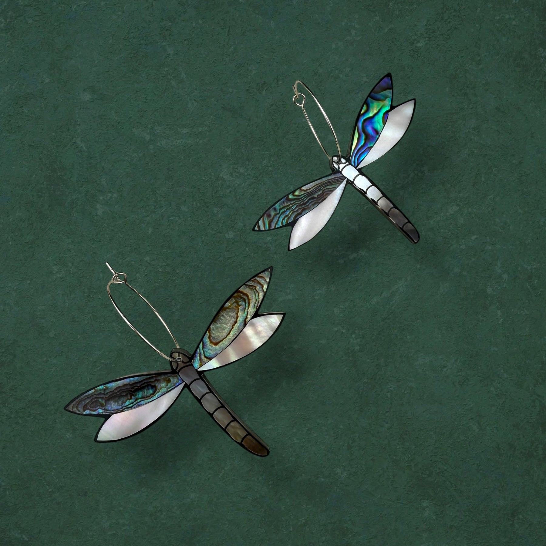 Aking Sinta gold Tutubi (Dragonfly) hoop earrings with intricate wing details, displayed against a moody dark green background.