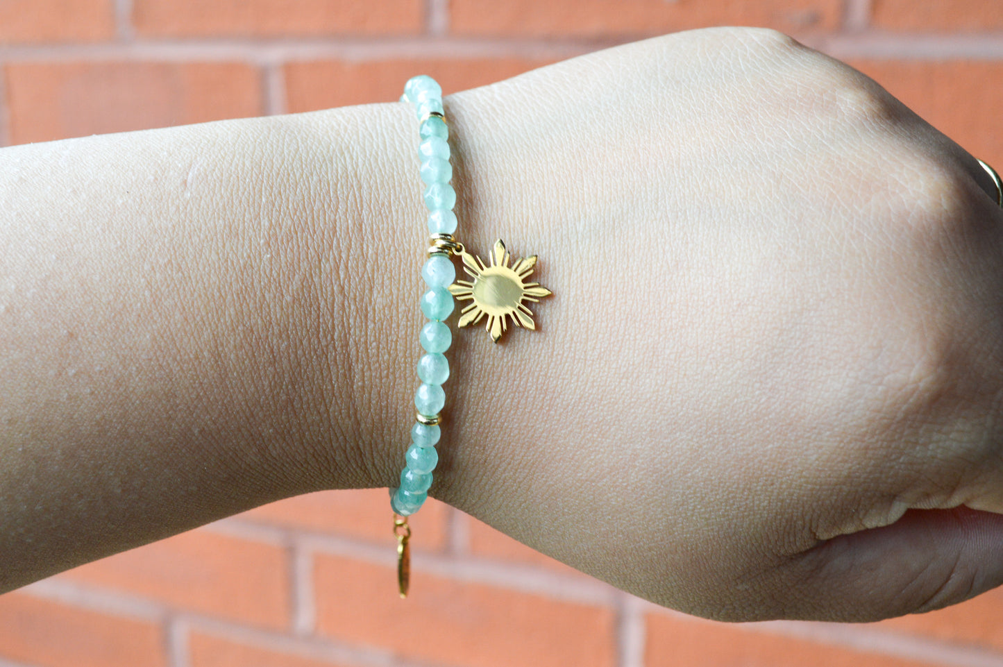 Close-up of hand wearing Aking Sinta Green Aventurine Bracelet with Araw sun charm, highlighting natural green stone beads and stretch fit