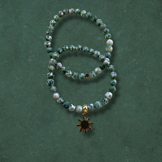Close-up of Aking Sinta Green Spot Jasper Stretch Bracelet, plain and with Araw sun charm, on green background, highlighting natural stone beads and Philippine-inspired design