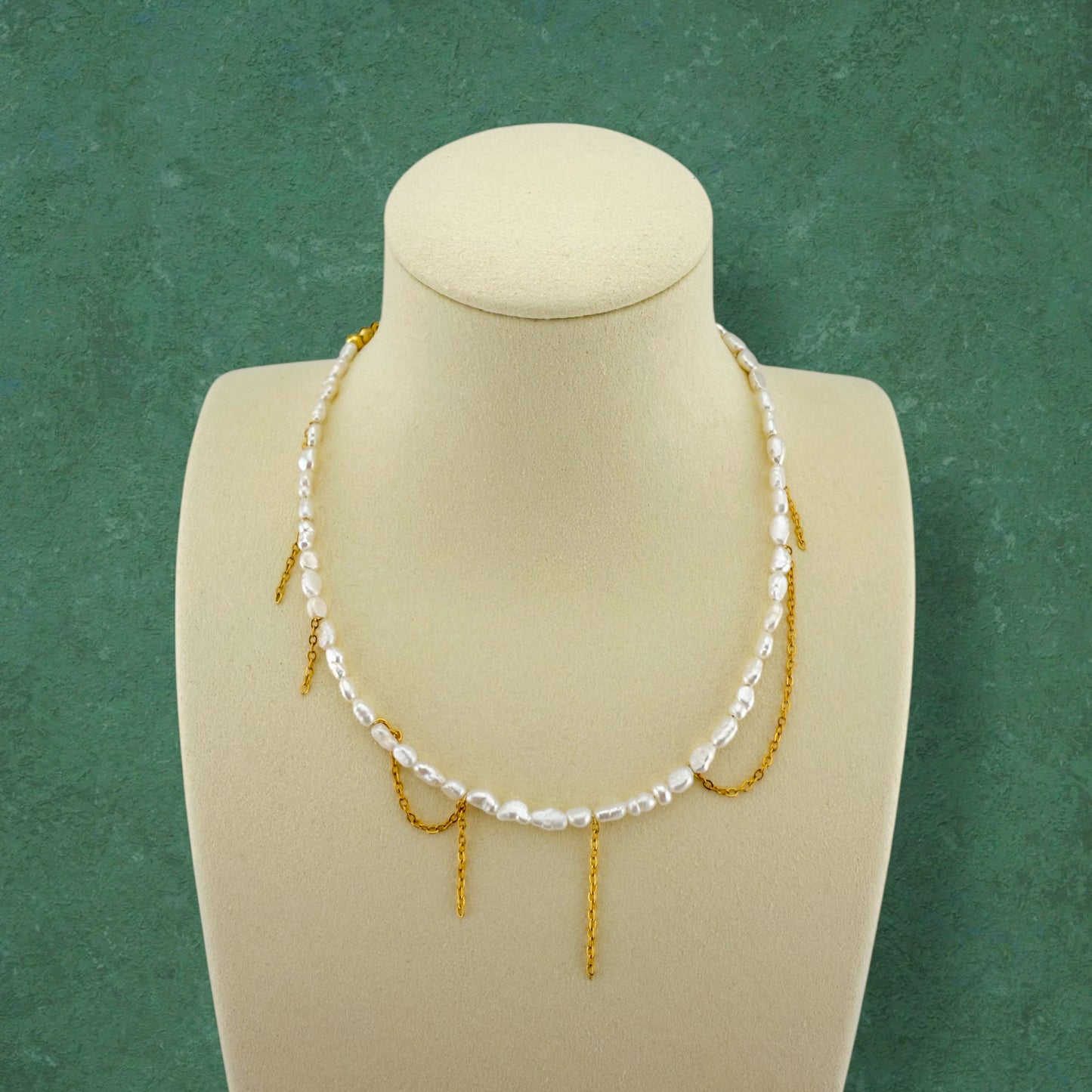 Kacey’s Asymmetrical Fringe Rice Pearl Necklace by Aking Sinta, displayed on a white jewelry bust to show the cascading, tiered fringe design.