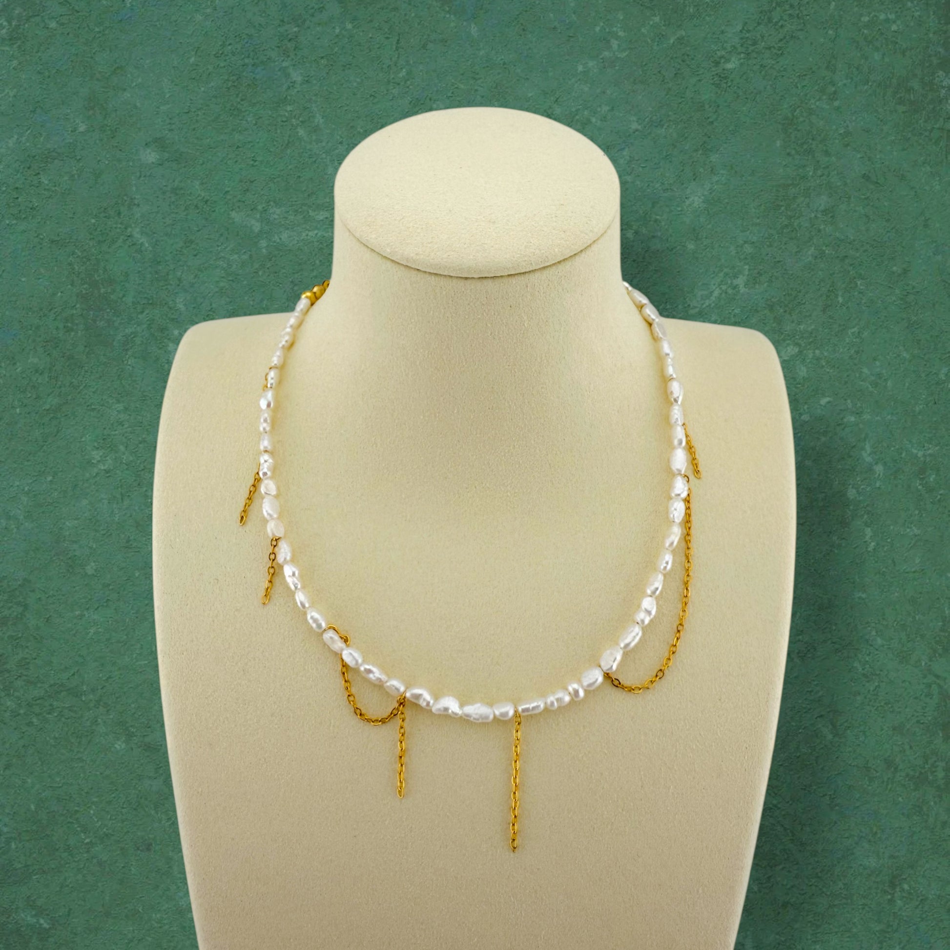 Kacey’s Asymmetrical Fringe Rice Pearl Necklace by Aking Sinta, displayed on a white jewelry bust to show the cascading, tiered fringe design.