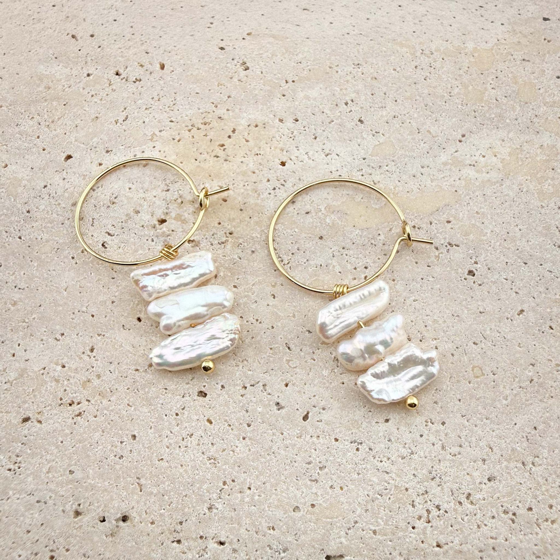 Side-by-side comparison of gold and silver Triple Flat Keshi Pearl hoop earrings on a white marble background.
