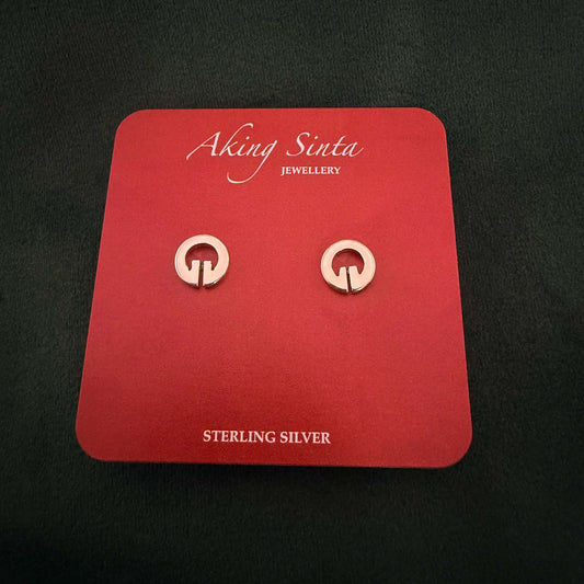 A pair of Aking Sinta sterling silver Lingling-O stud earrings on a red branded display card. These traditional Filipino-inspired circular studs feature the iconic ancient symbol, set against a dark textured background.