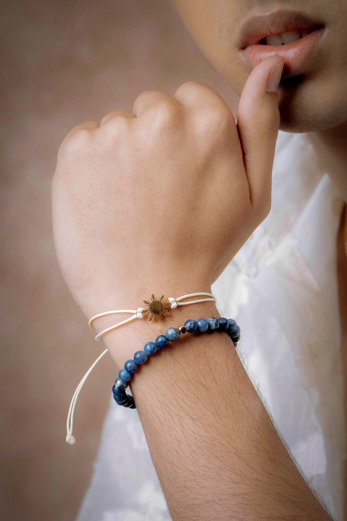 Close-up of a man wearing a Sodalite blue stone stretch bracelet while resting his hand on his chin; styled with a white polo shirt for a clean, modern men's accessory look by Aking Sinta