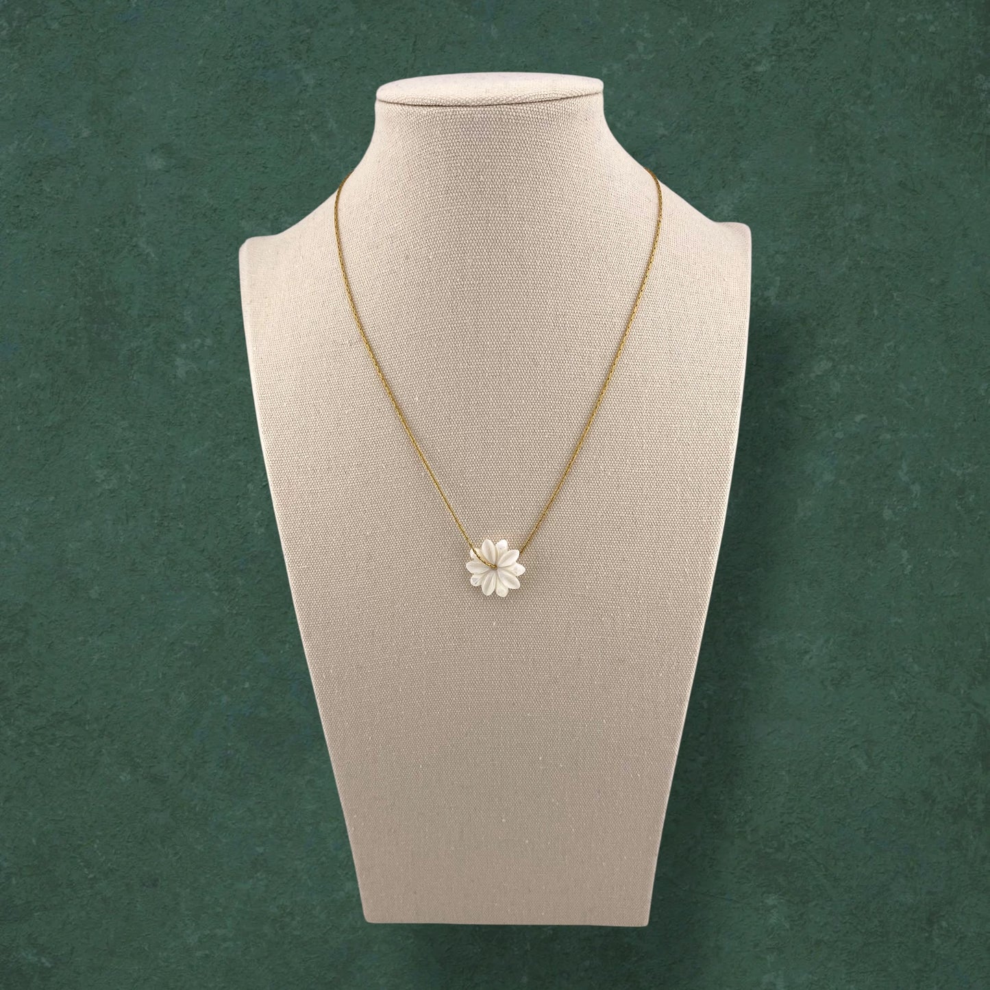 Aking Sinta Floating Sampaguita necklace with a hand-carved Mother of Pearl jasmine bud on a gold chain, displayed on an elongated white jewelry bust.
