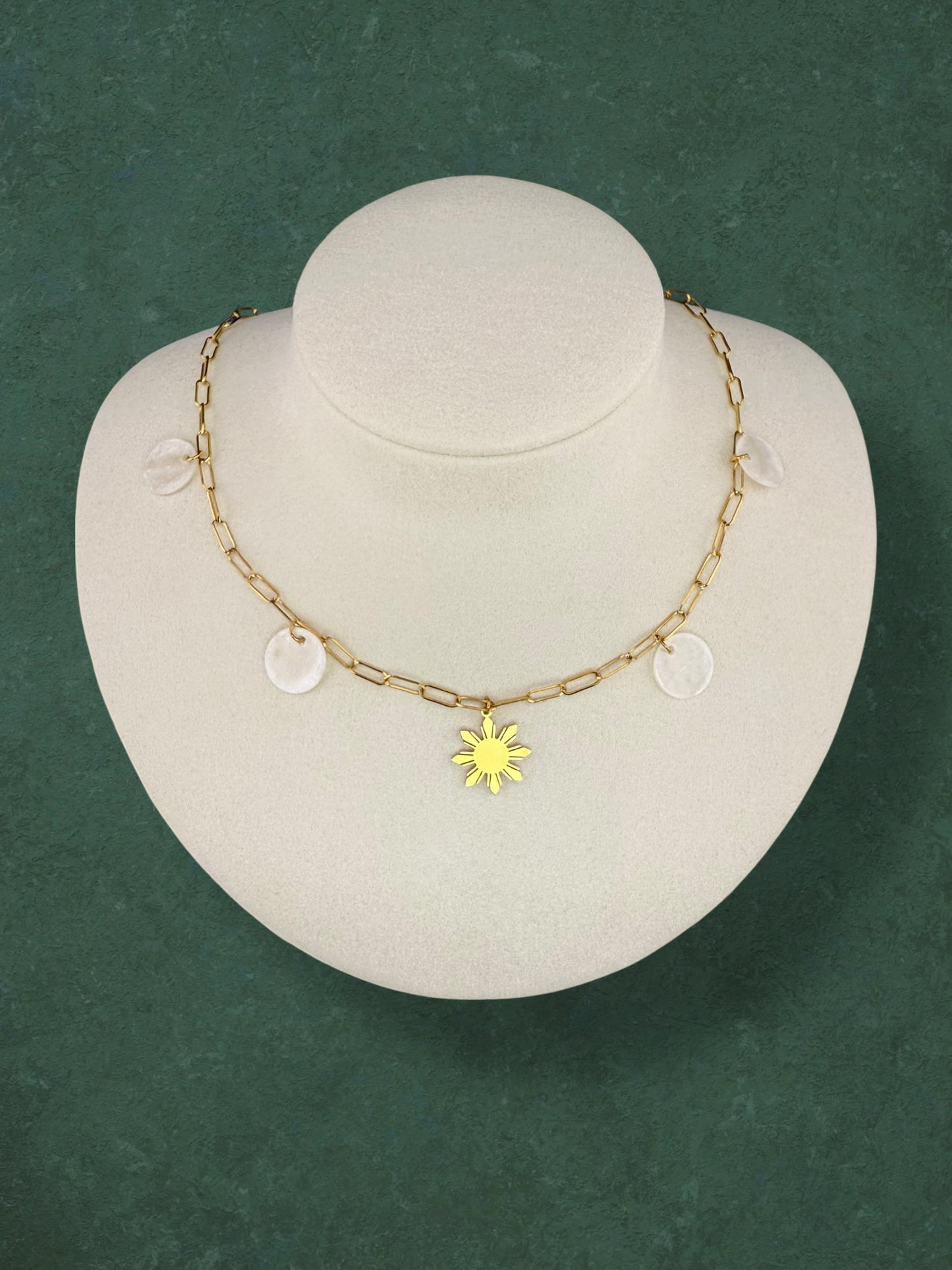 Aking Sinta Paperclip Chain Necklace with Araw sun and Capiz Shell charms displayed on neck-shaped jewellery holder on green background, highlighting delicate design and Philippine-inspired craftsmanship