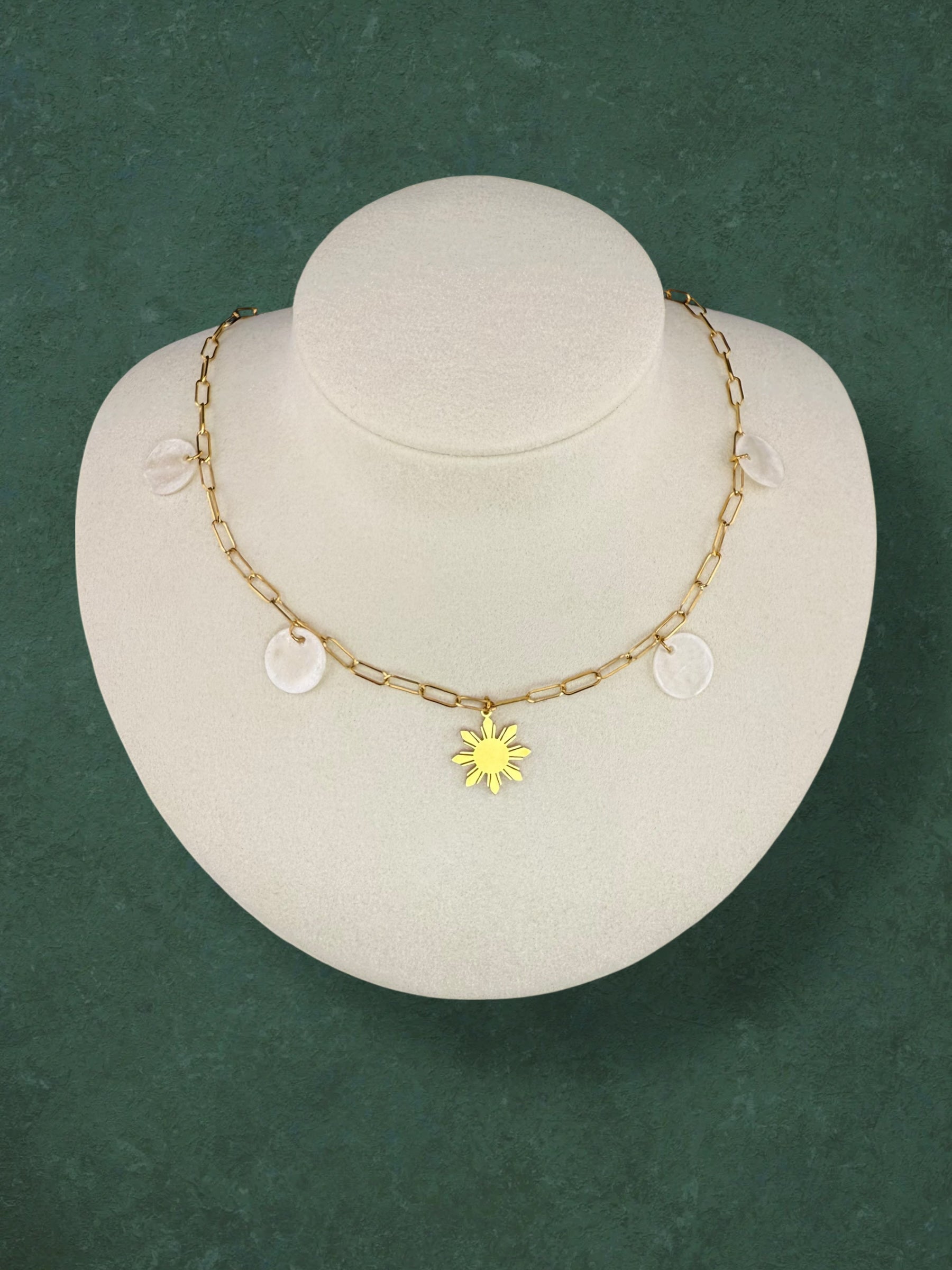 Aking Sinta Paperclip Chain Necklace with Araw sun and Capiz Shell charms displayed on neck-shaped jewellery holder on green background, highlighting delicate design and Philippine-inspired craftsmanship