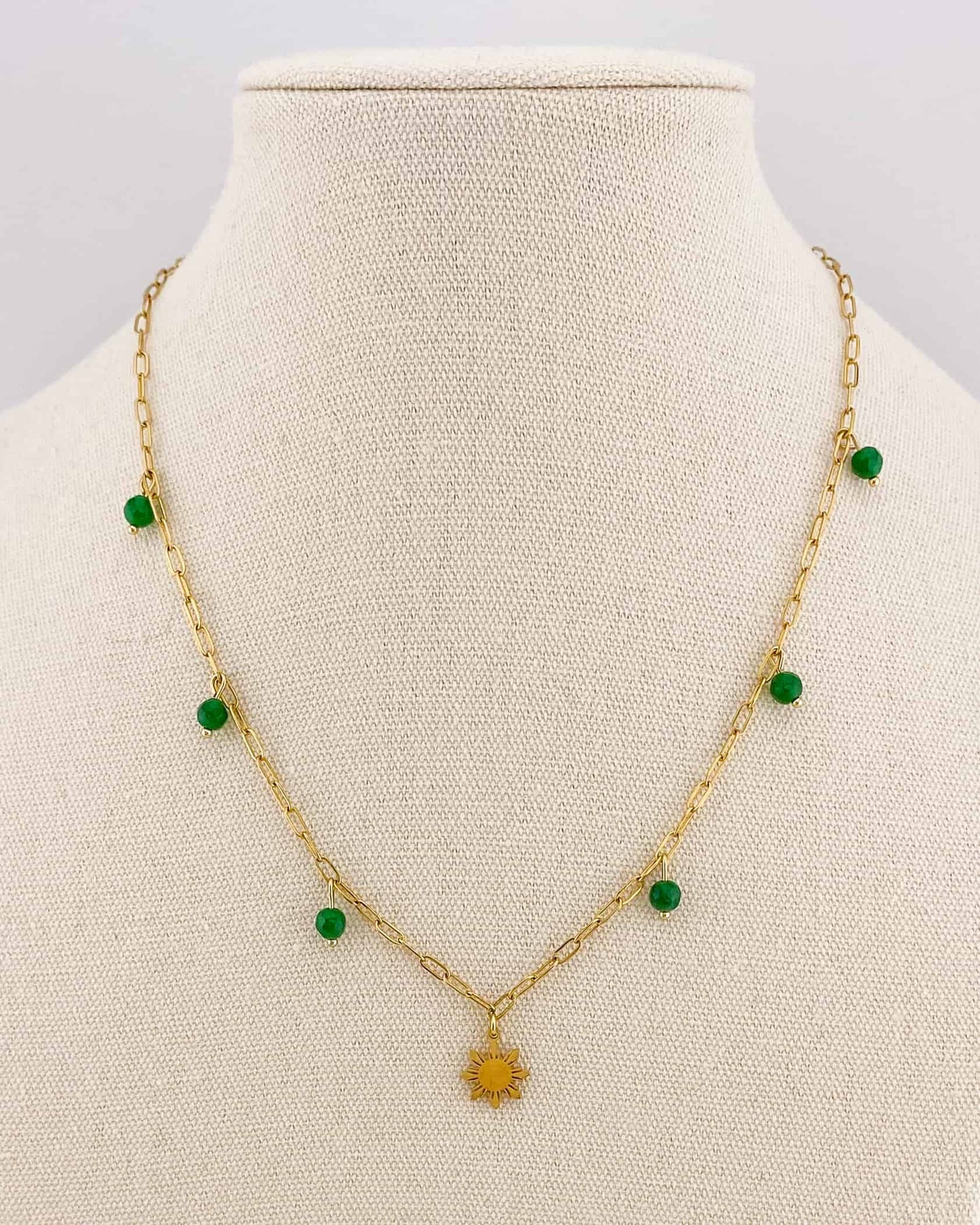 Side-angle close-up of an Aking Sinta gold paperclip necklace on a white bust; shows the profile of the gold Araw charm and the green jade bead fixed to the link, highlighting the polished finish and chain thickness.