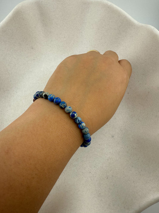 Aking Sinta plain blue Imperial Jasper stretch bracelet with white speckled patterns, worn on a wrist to show fit and natural stone texture.