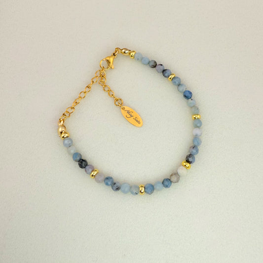 A minimalist Aking Sinta Dirty Aquamarine beaded bracelet without a charm, featuring a mix of light blue and sky blue gemstones with natural cloudy inclusions; finished with a gold extender chain and a teardrop tag engraved with "Aking Sinta."