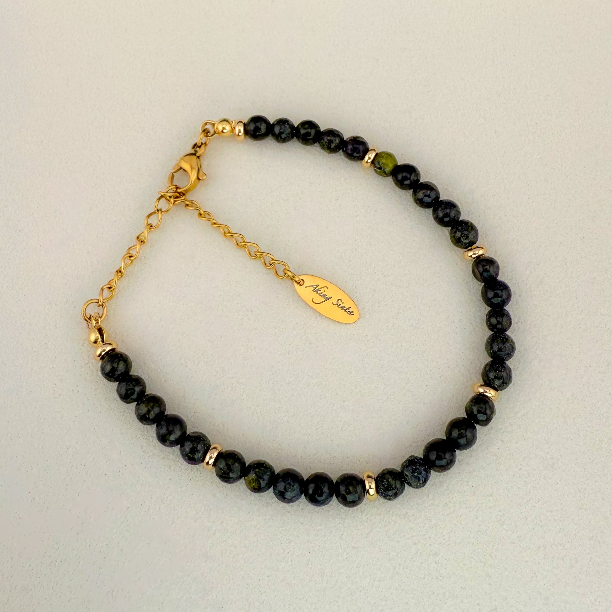 A minimalist Aking Sinta Serpentine beaded bracelet without a charm, featuring translucent lime and olive green gemstones with soft natural clouding; finished with a gold extender chain and a teardrop tag engraved with "Aking Sinta."