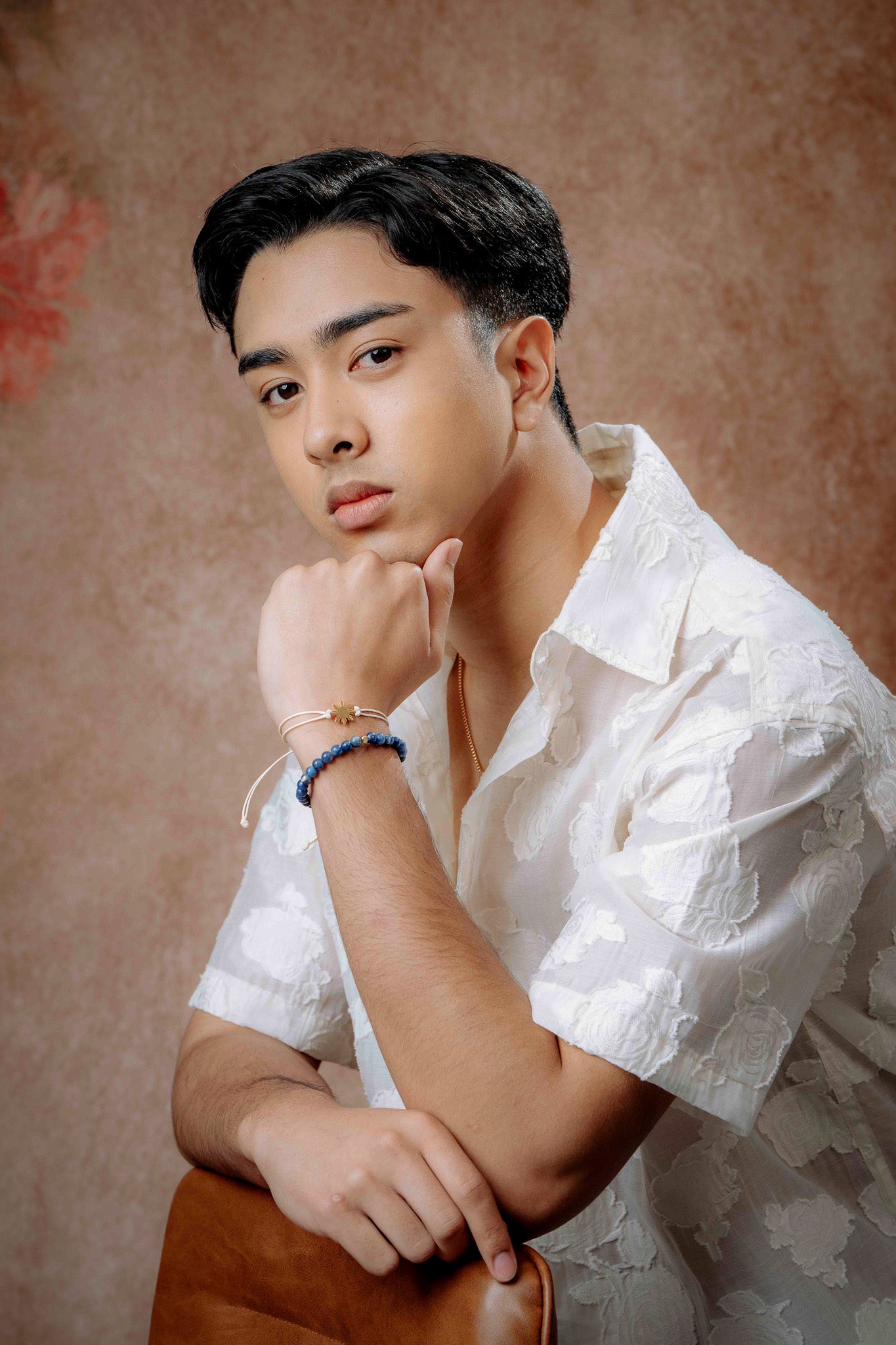 A man in a white polo shirt captured in a thoughtful thinking pose, wearing the plain Sodalite blue stone stretch bracelet; a minimalist and masculine jewelry piece by Aking Sinta