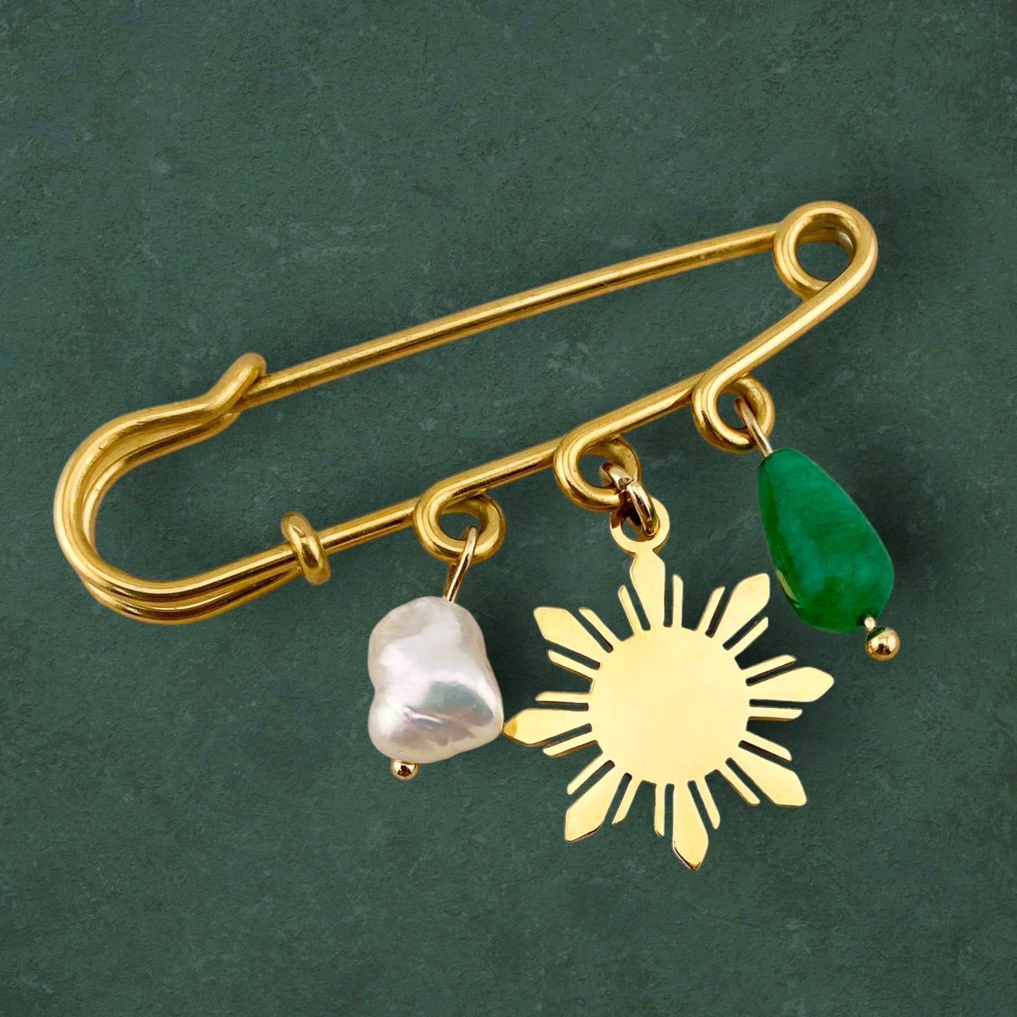 Aking Sinta Safety Pin Brooch featuring pearl, Araw sun, and jade charms, displayed on dark green background, highlighting intricate design and Philippine-inspired details